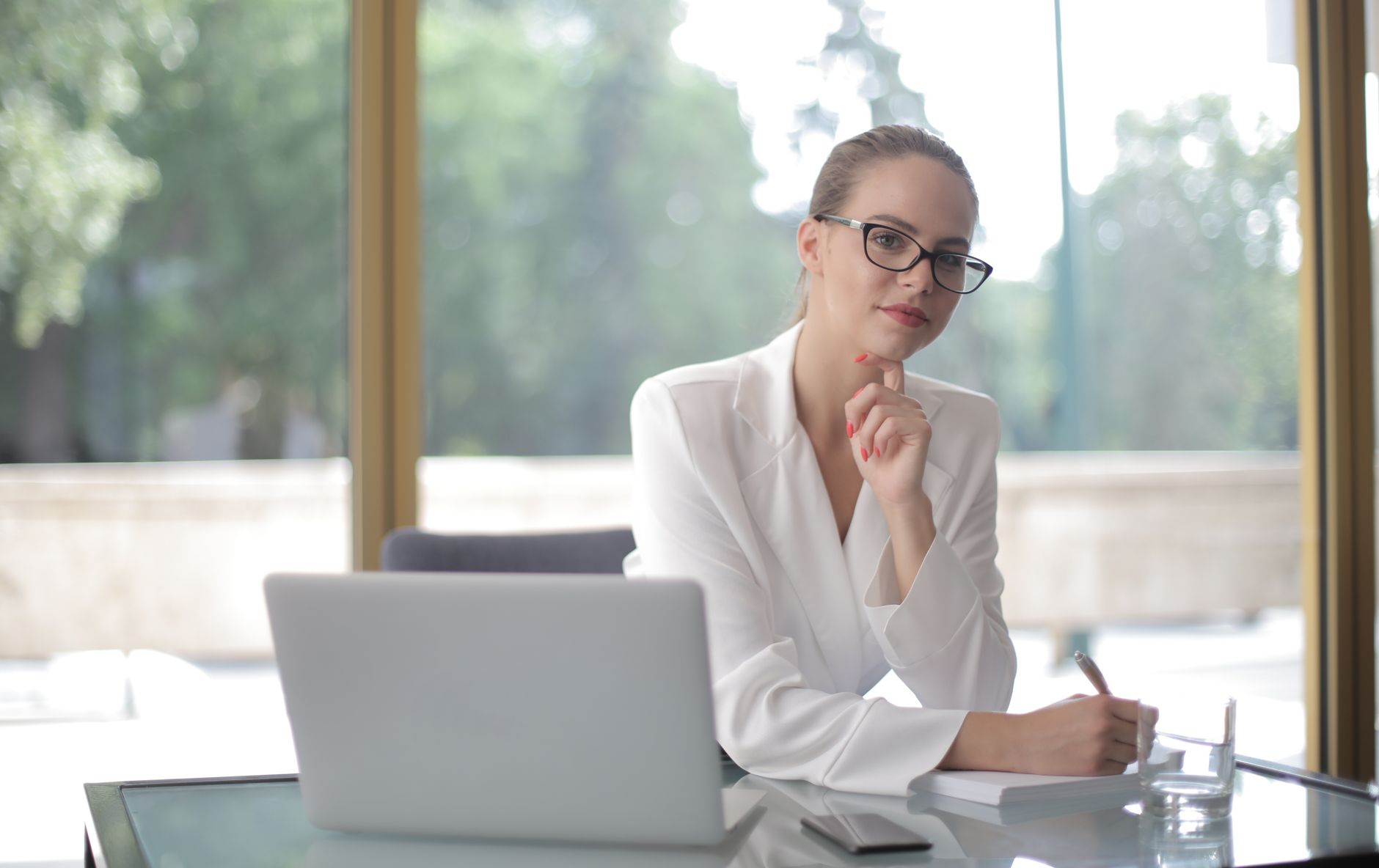 Confident woman in glasses working at a desk, embodying modern professionalism.