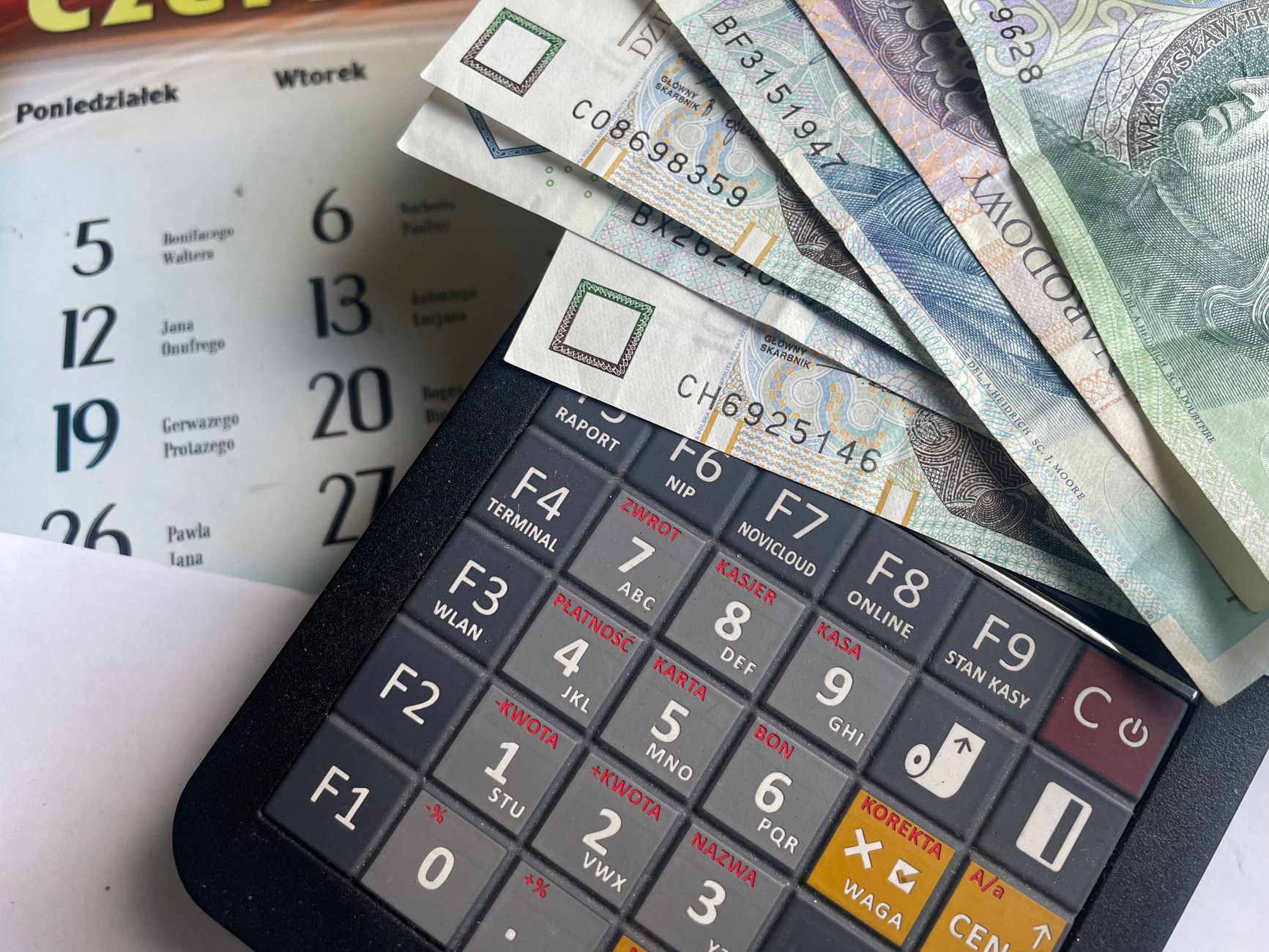 Banknotes resting on a calculator beside a calendar