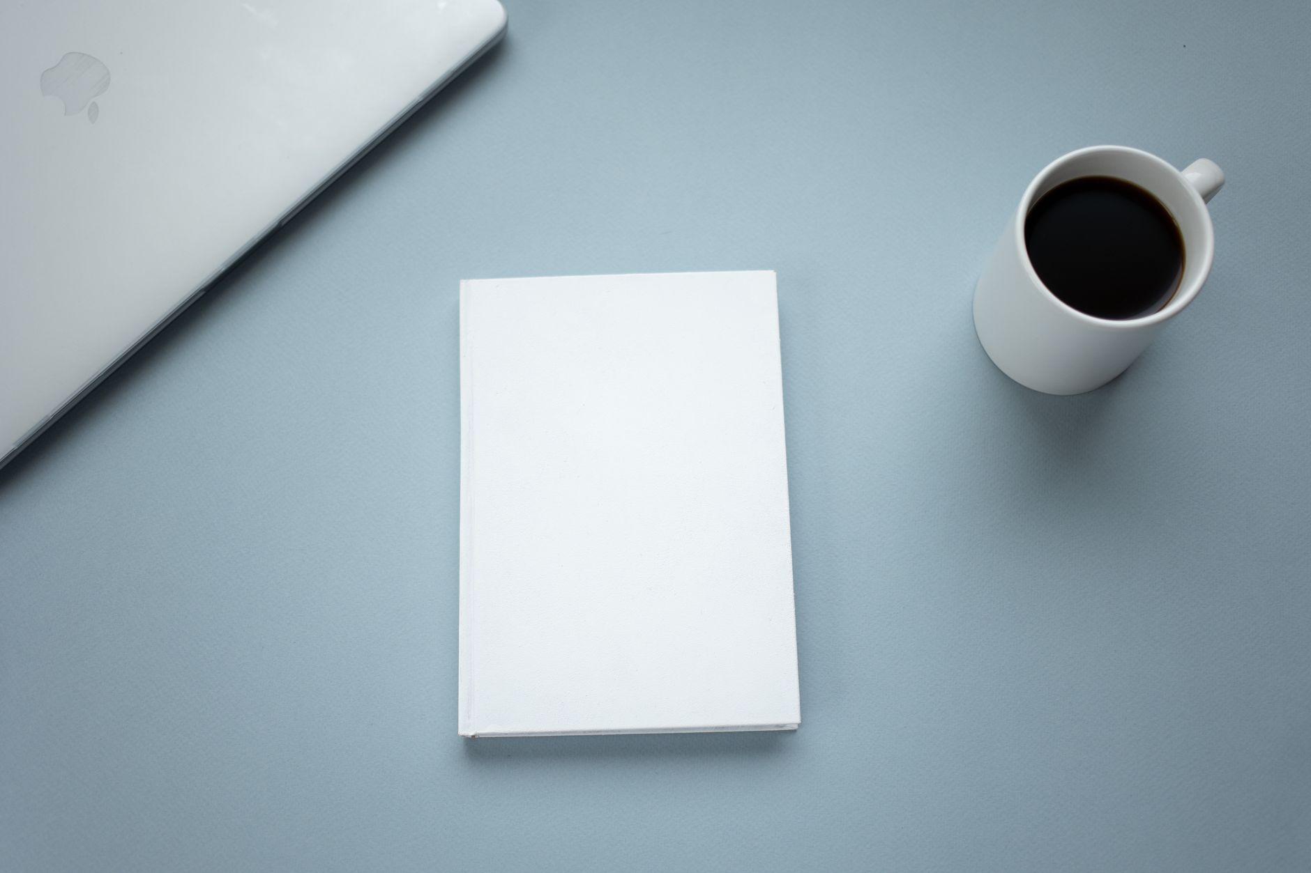 A small notebook open to a page with only a few short lines written, next to a cup of coffee