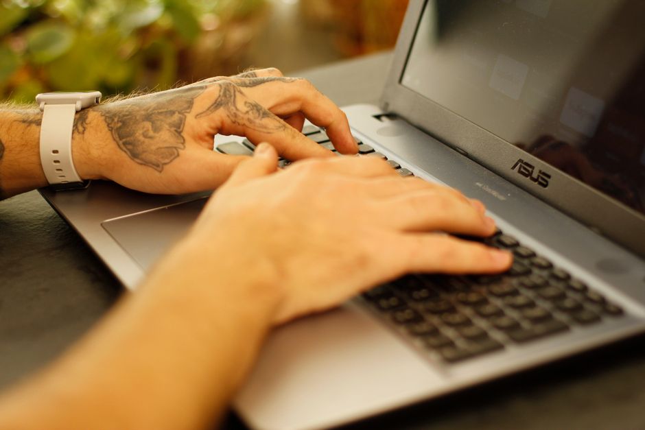 Hands type a message on a laptop keyboard.