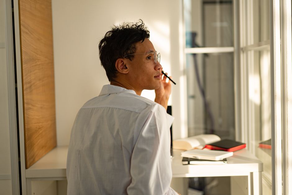 A thoughtful professional pauses beside books while considering a decision.