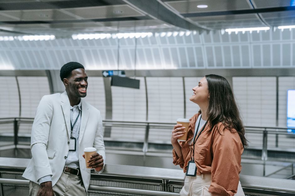 Two colleagues talk over coffee in a bright workplace.
