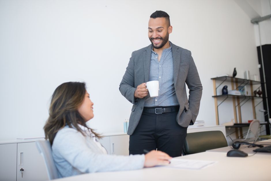 Two professionals smiling during a conversation in an office.