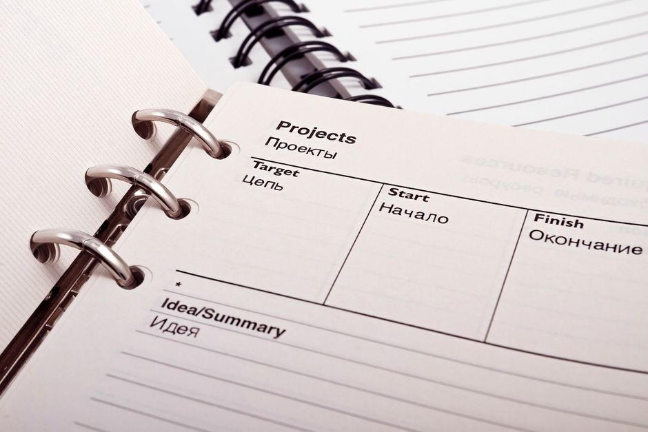 An open planner containing handwritten project schedules.