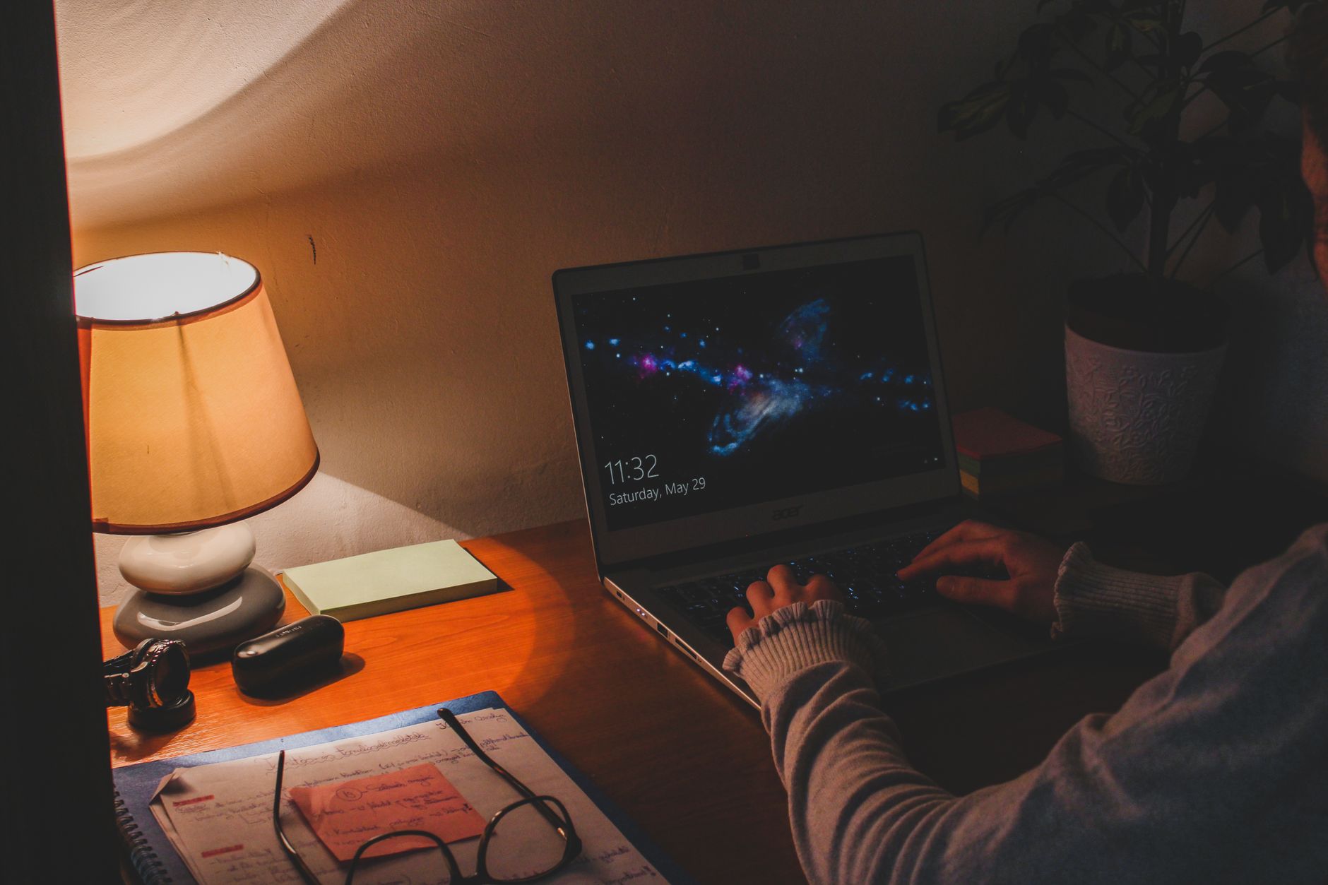 A person typing at a laptop late at night, screen glow lighting their face in an otherwise dark room