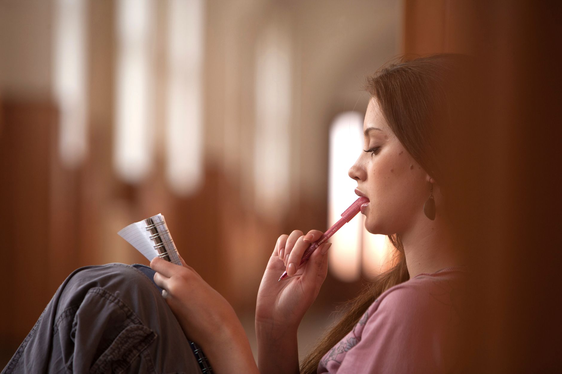 A woman pauses with a pen and notebook while thinking.