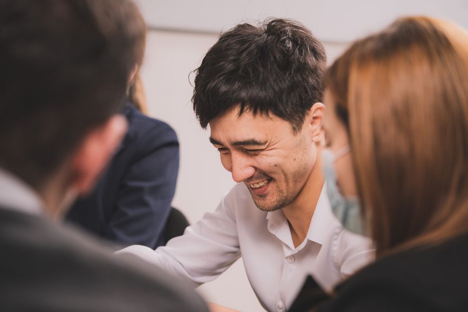 Colleagues smiling during a collaborative office meeting.
