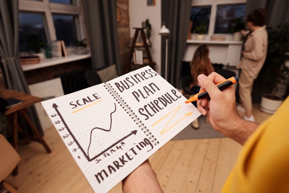 A person holding a notebook with planning notes and a graph.