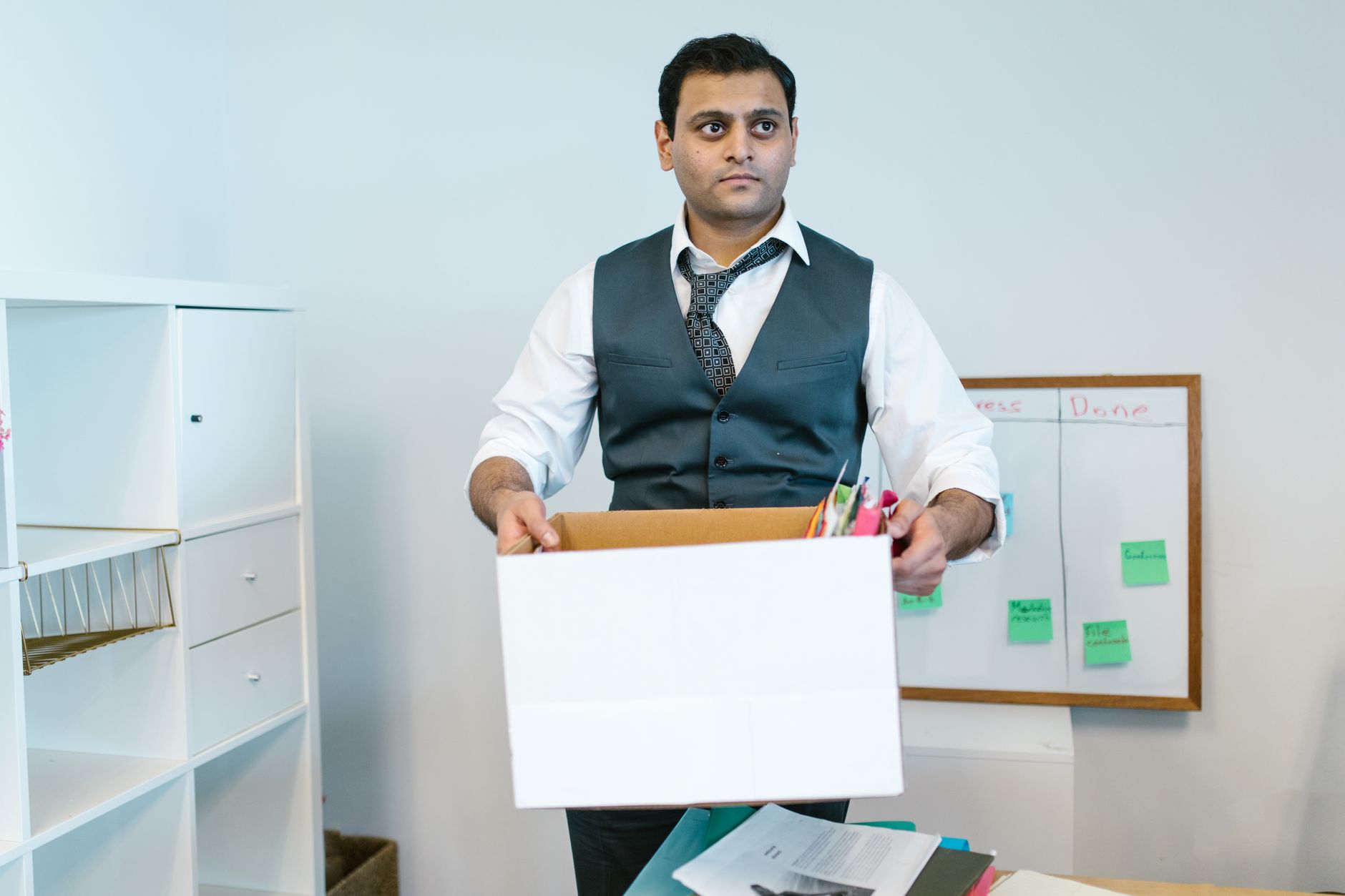 Two colleagues talking calmly in an office, one taking notes on a clipboard while the other speaks
