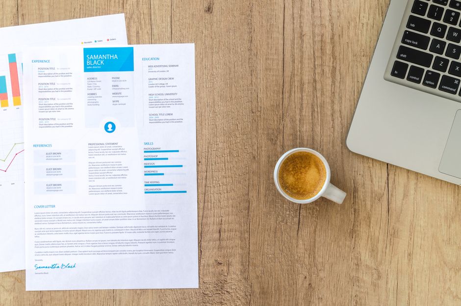 A resume, laptop, and coffee arranged on a work desk.