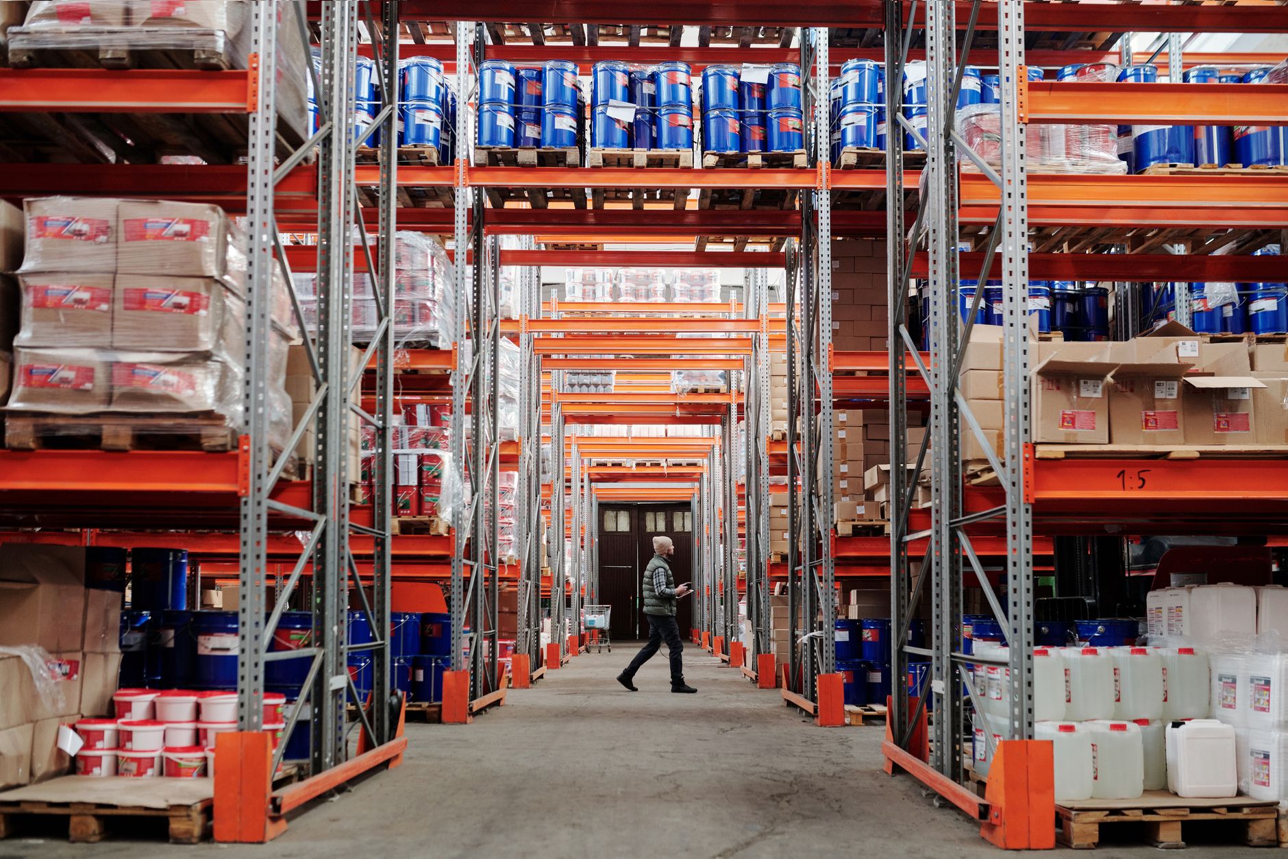 A hardware store aisle lined with shelves of tools, fittings, and building supplies stretching toward the back of the store