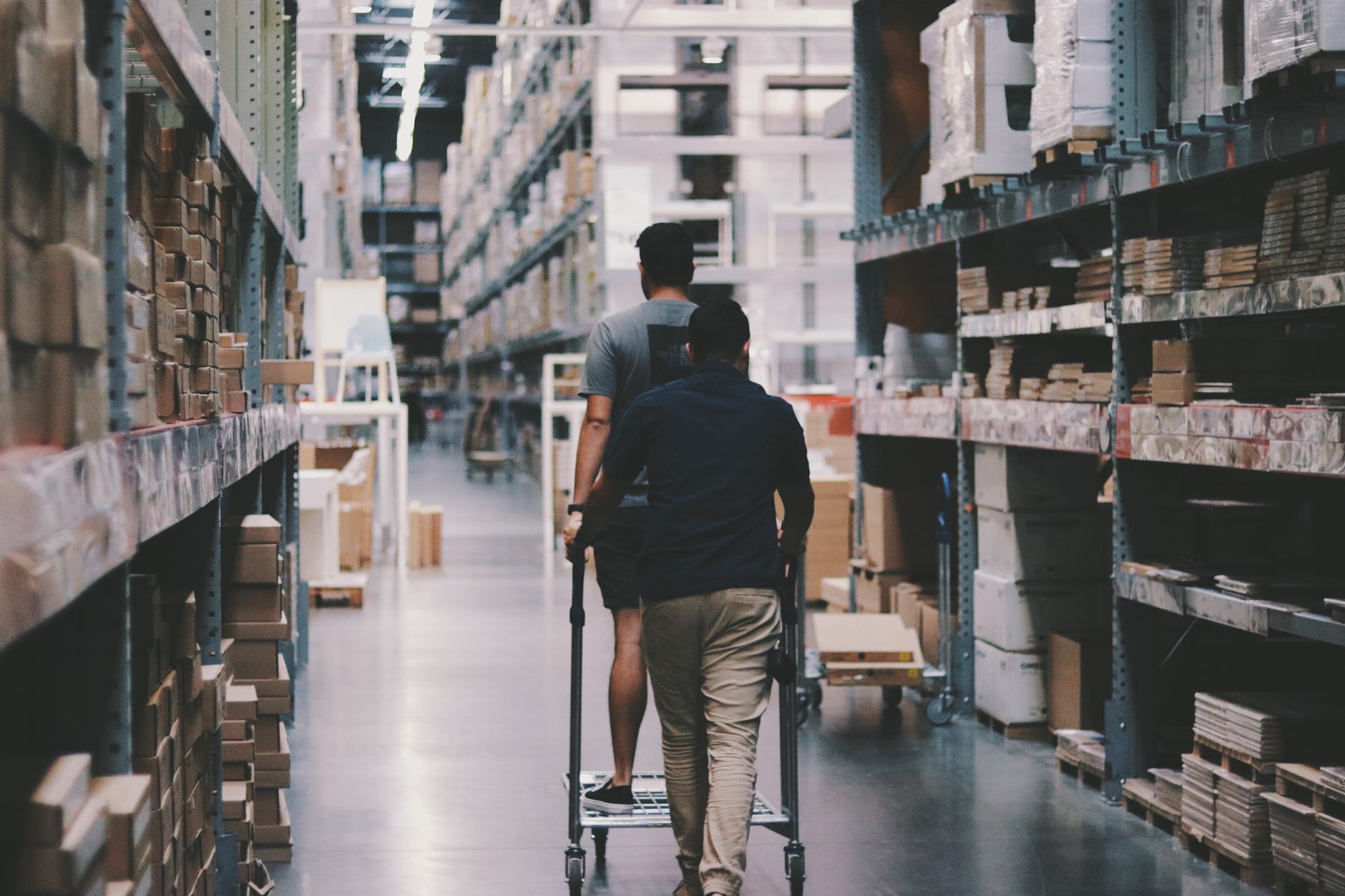 A worker in a safety helmet and high-visibility vest moving stacked material in a warehouse