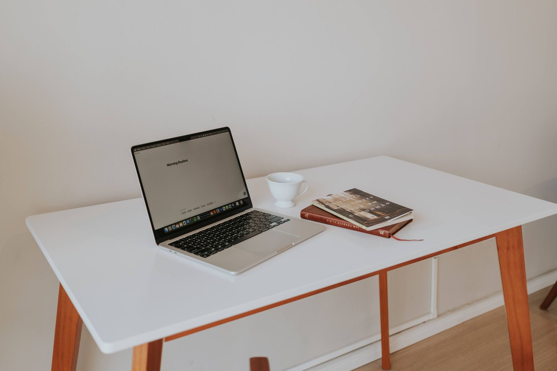 A hand writing a short numbered list in a notebook on a wooden table beside a cup of coffee