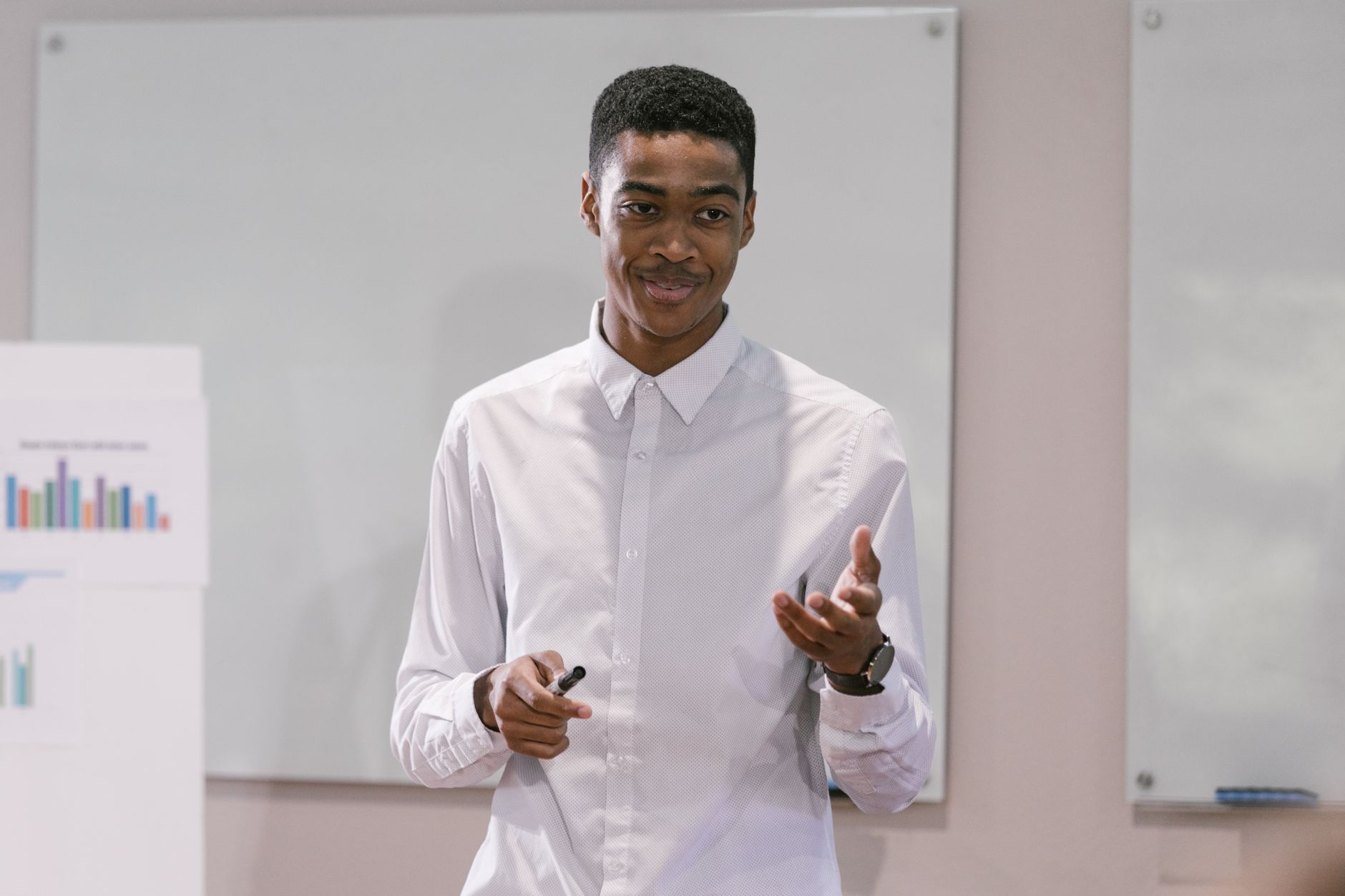 A confident young man presenting in a business setting, engaging with an audience.