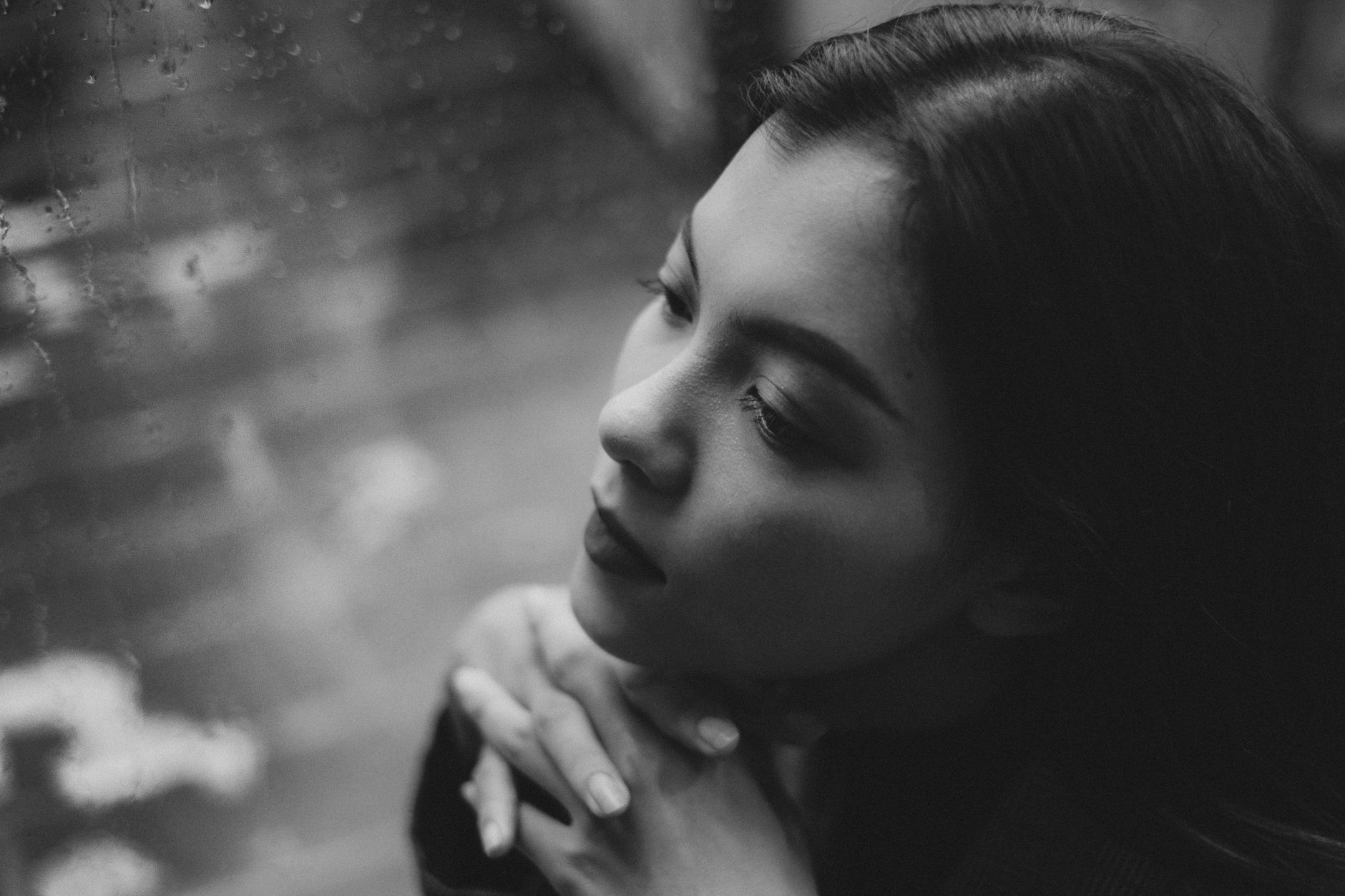 A young man sits alone outdoors, looking down at his phone with a subdued expression after reading a message.