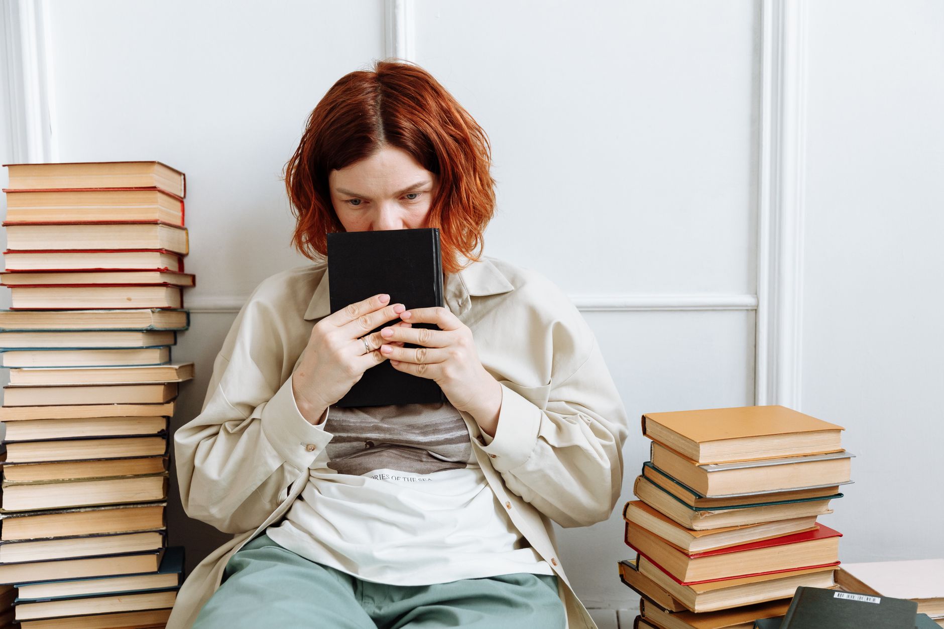 A person sitting at a desk deeply focused, reading and taking notes from a book