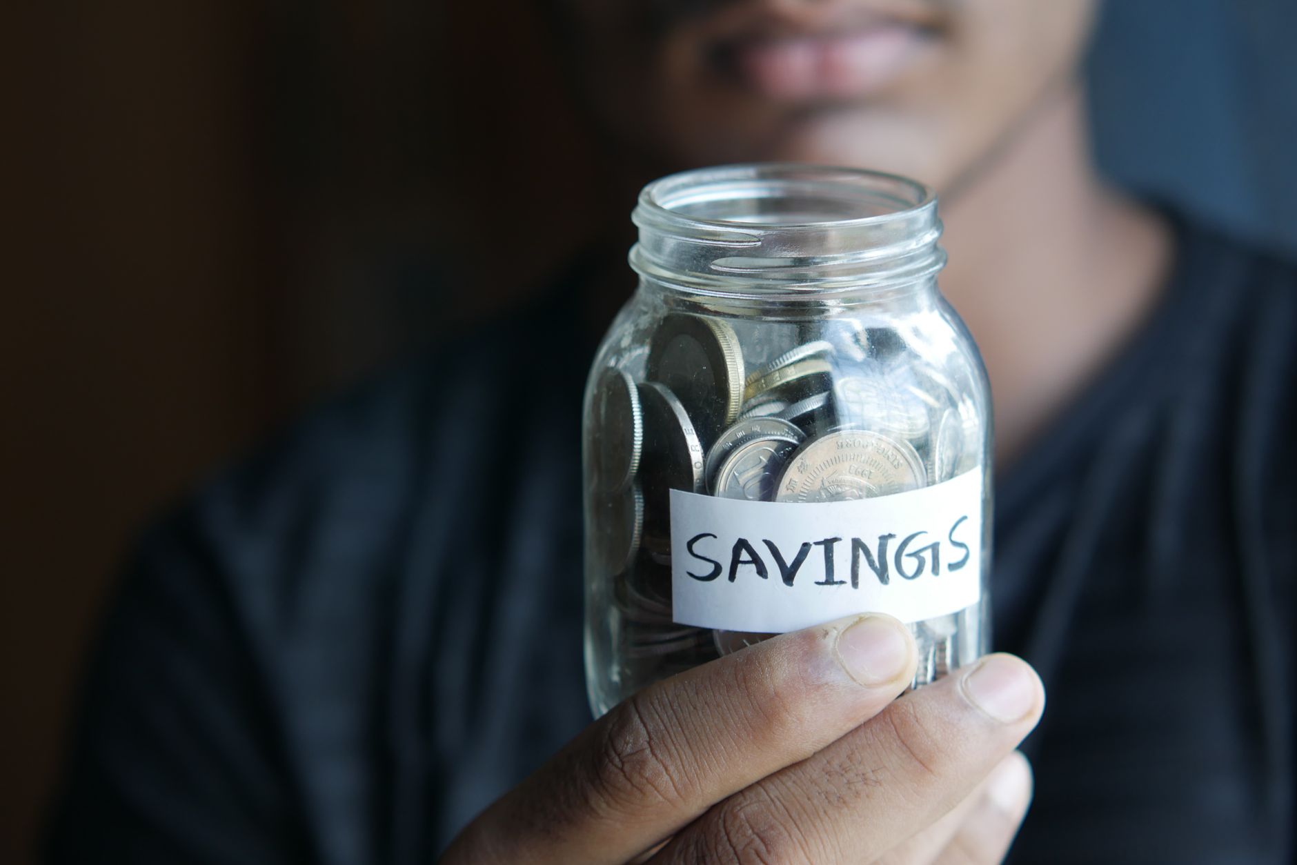 Coins stacked in ascending piles next to a small notebook showing a written savings target
