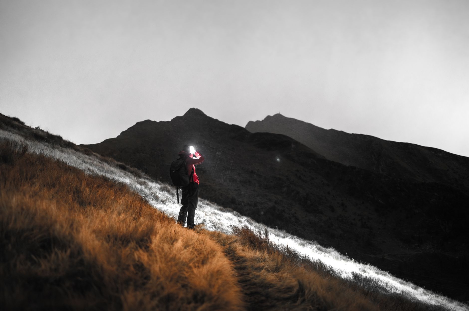 A lone hiker walking along a misty mountain ridge trail with no one else in view