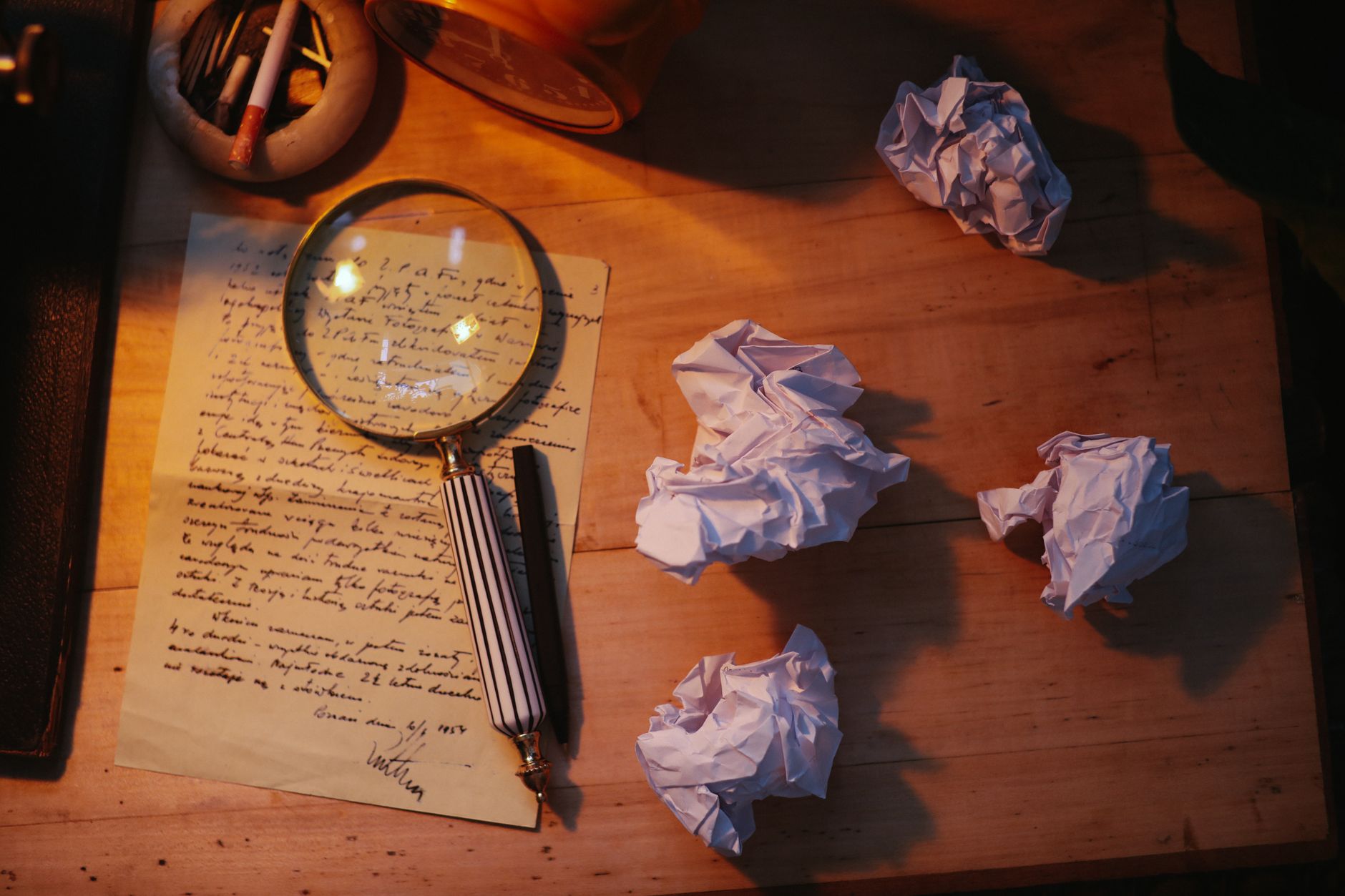 Close-up of a hand writing in a notebook next to an open laptop on a desk