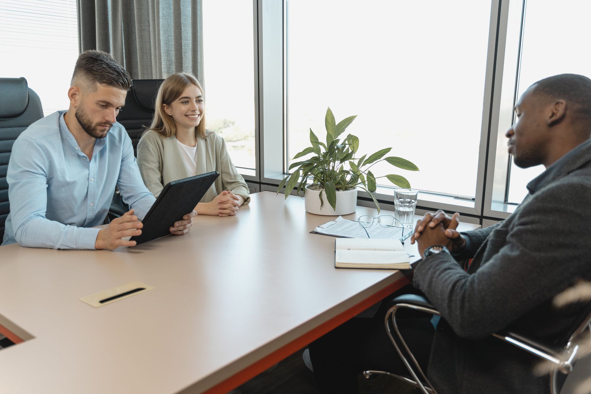A recruiter sits at a desk with a headset and a laptop, taking notes on a printed candidate summary during a phone screen.