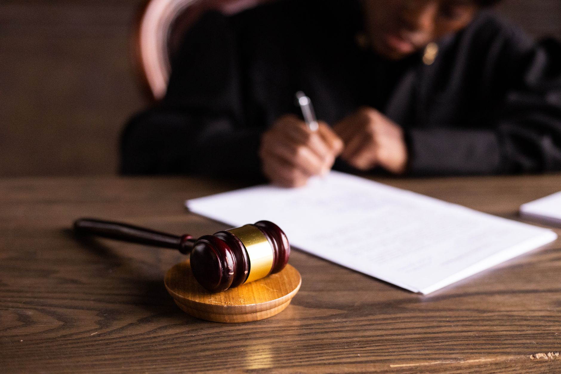 Close-up of a person's hands writing notes on a legal pad beside a laptop after a meeting