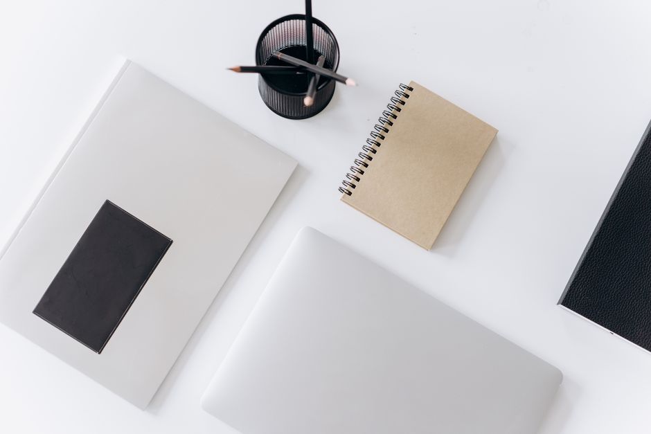 A laptop, open notebook, and pencils arranged on a desk.