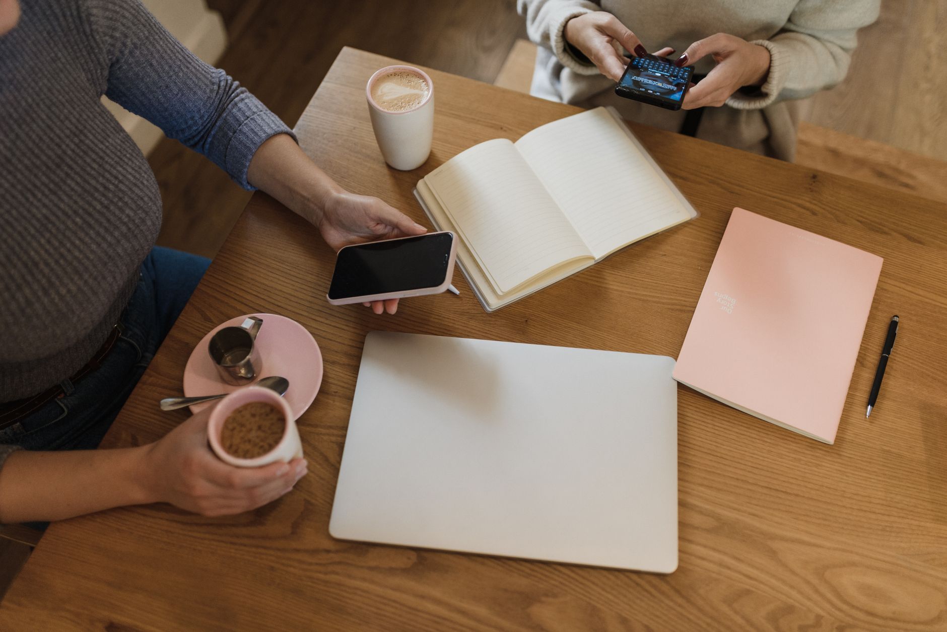 Two people sitting across a small table in a bright office, one taking notes on a pad while the other speaks