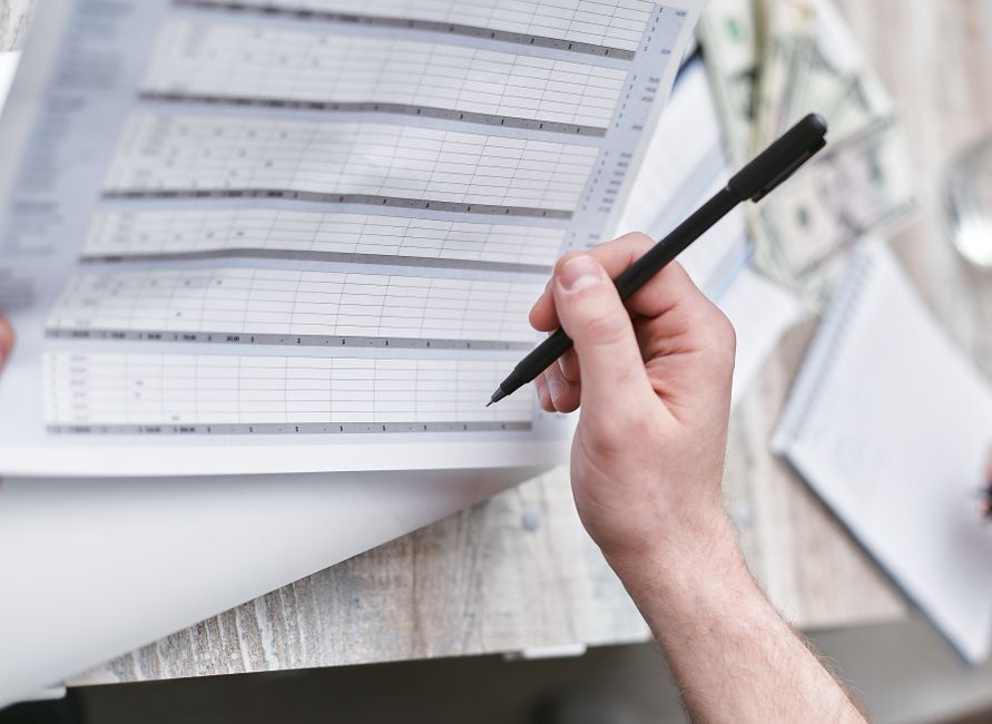 A professional records the next action while reviewing documents.