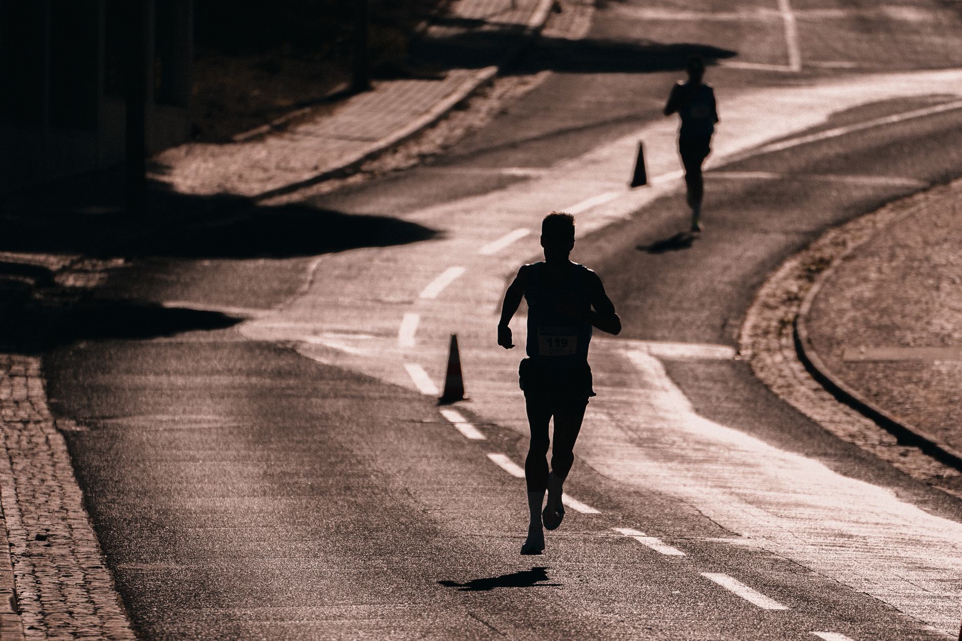 A line of runners mid-race on an open road, spread out and settled into their own pace