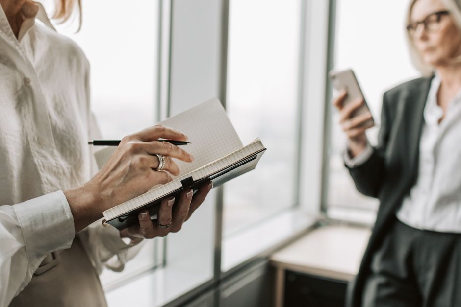 Colleagues review notes and a phone at a meeting table.