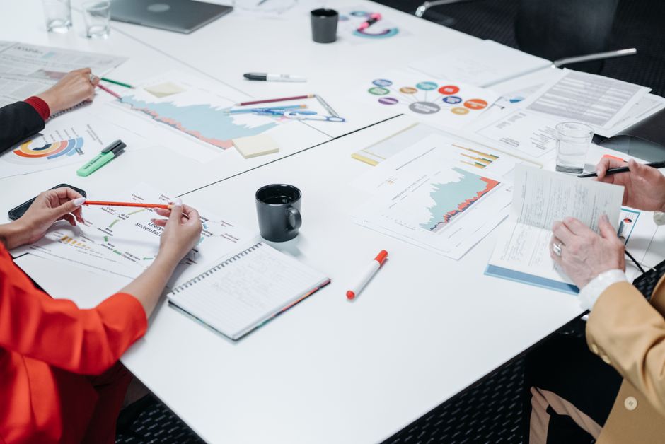 Charts, notebooks, and coffee arranged on an office meeting desk.