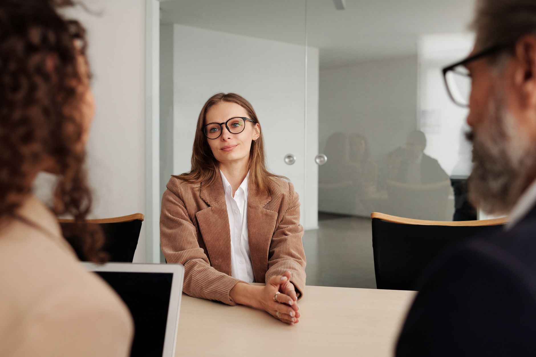 Three interviewers seated behind a table facing a candidate across from them in a bright office room