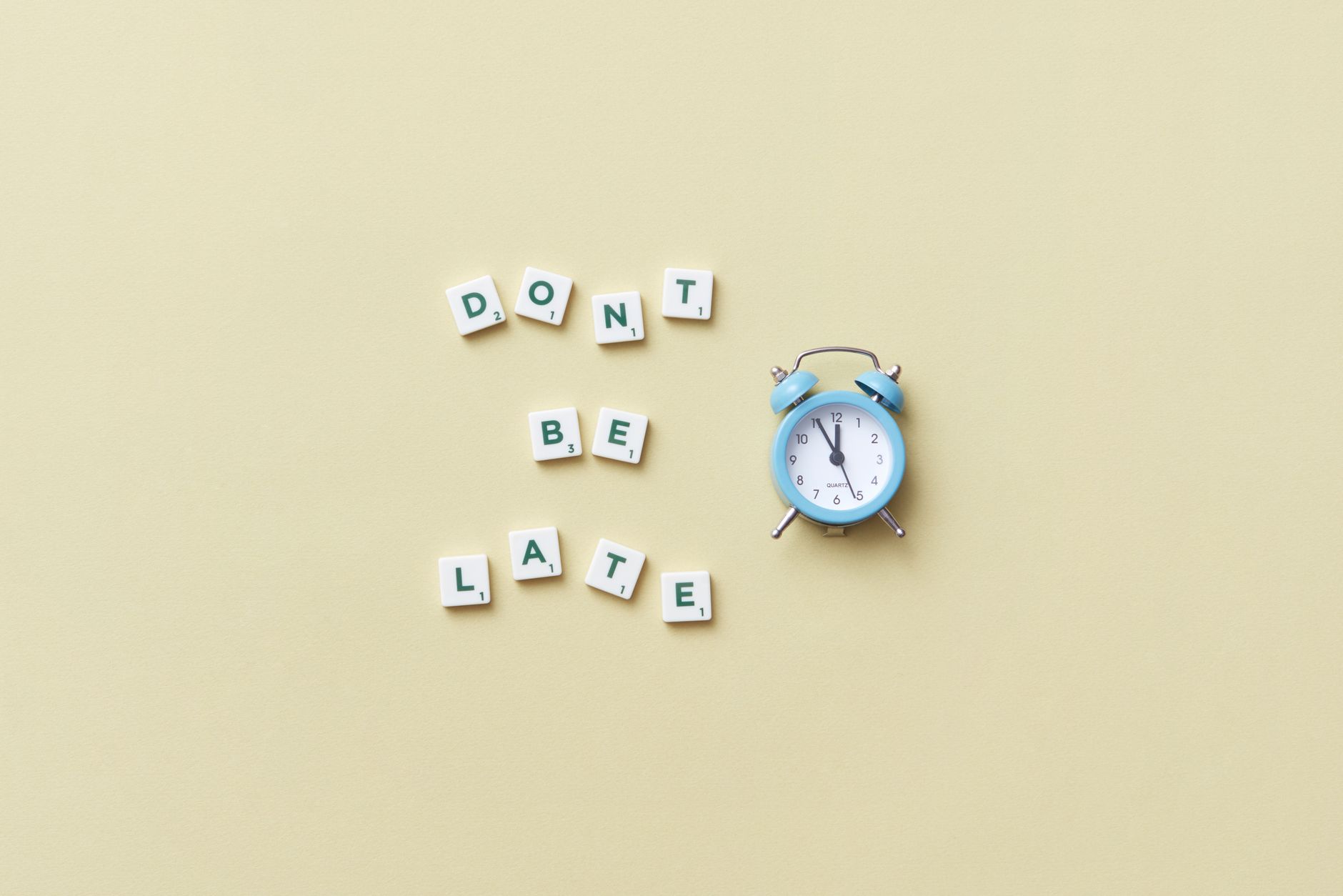 Blue alarm clock beside letter tiles that say do not be late