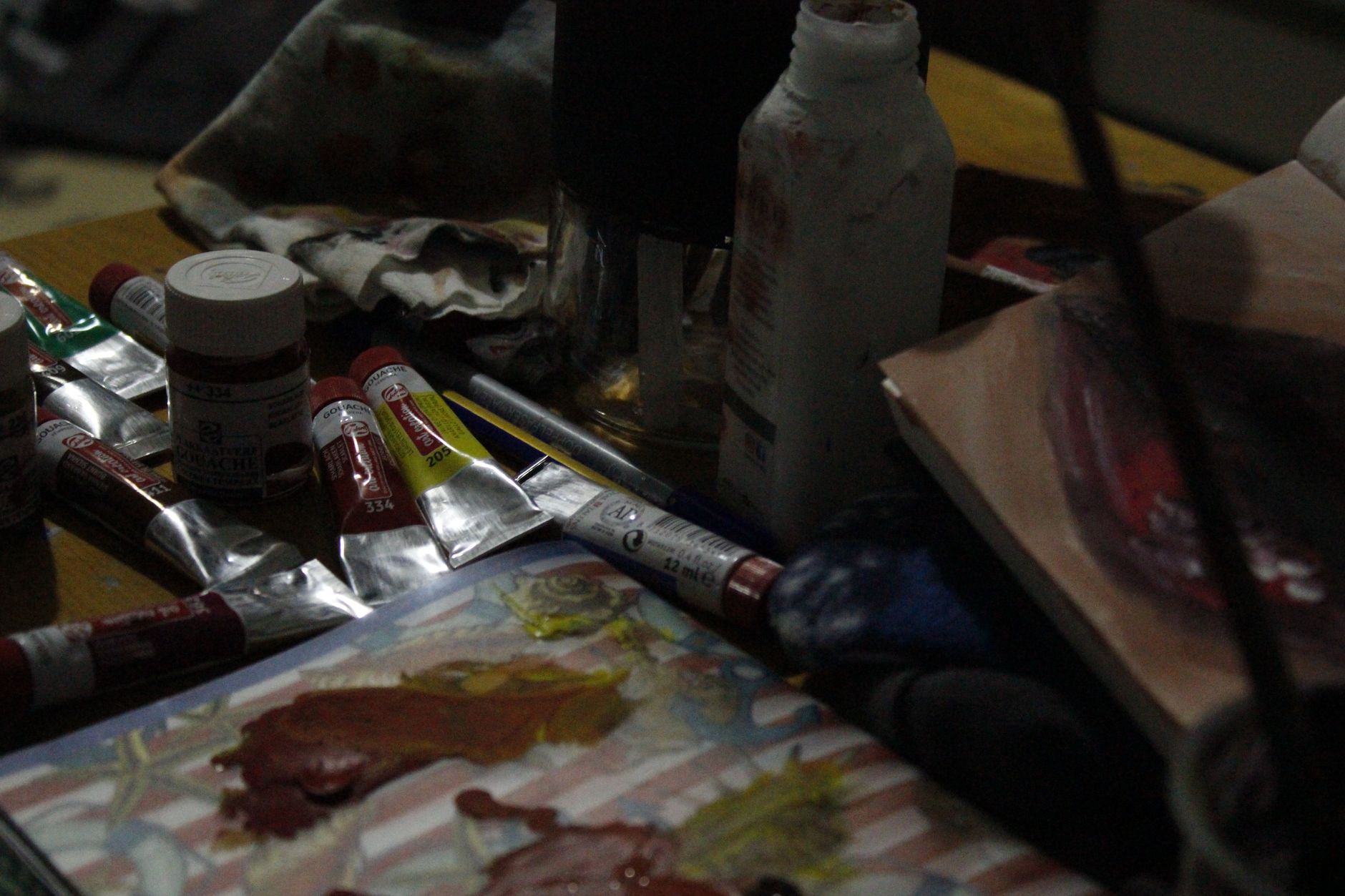Paint tubes and brushes on an active creative workspace.