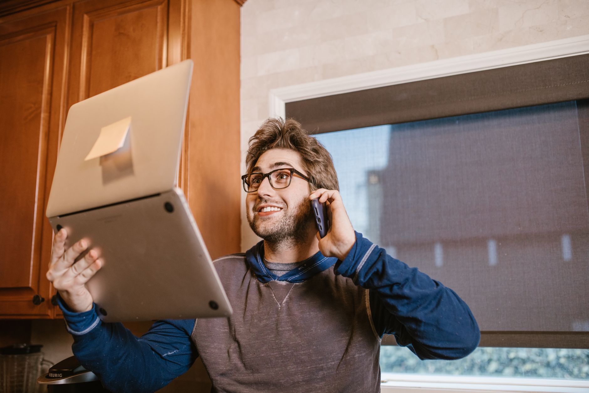 A professional in a blazer sits near a window, phone in hand and notebook open, mid-conversation during a call