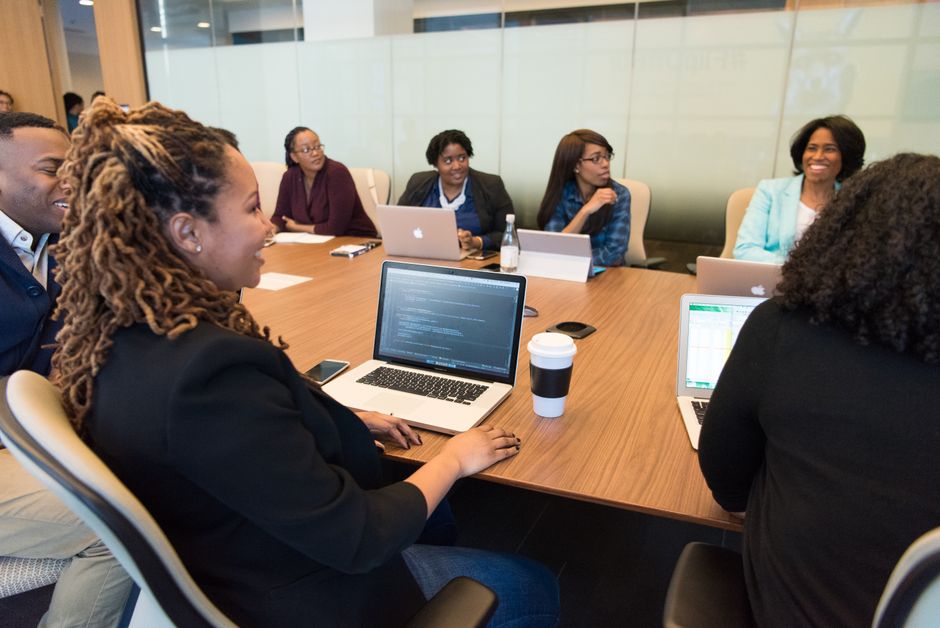 Colleagues working together with laptops at a conference table.