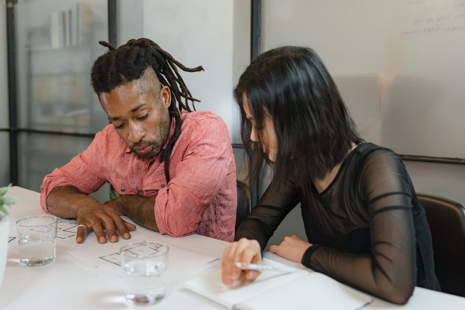 Two colleagues reviewing plans together at an office desk.