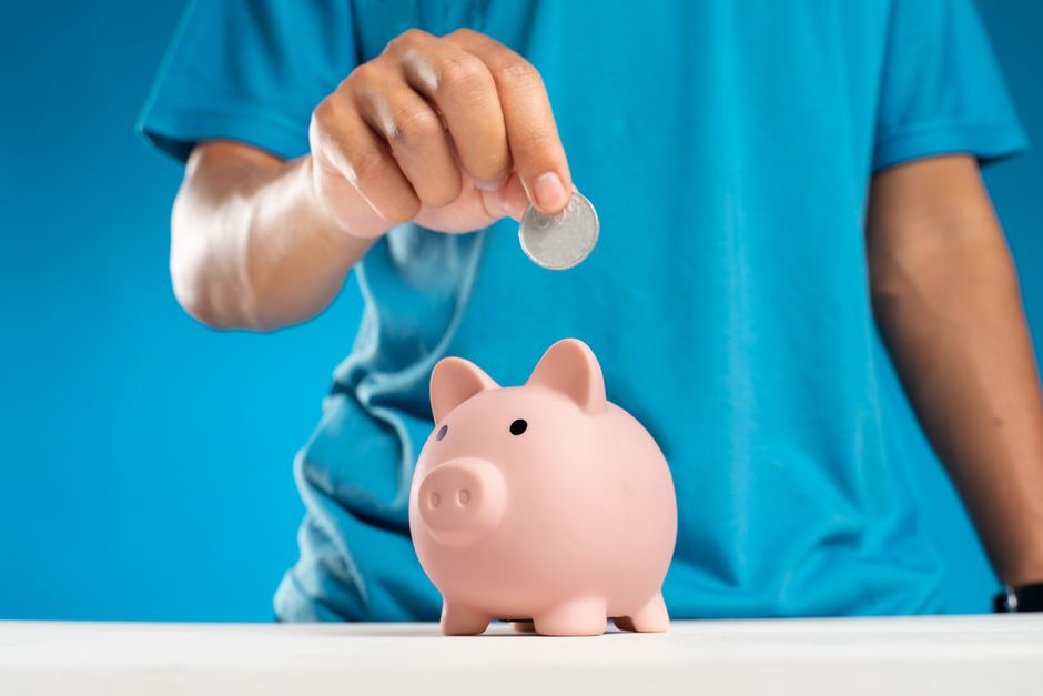 A coin enters a savings jar as a simple image of repeated contributions.
