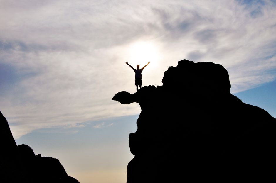 A person celebrates reaching a mountain summit.