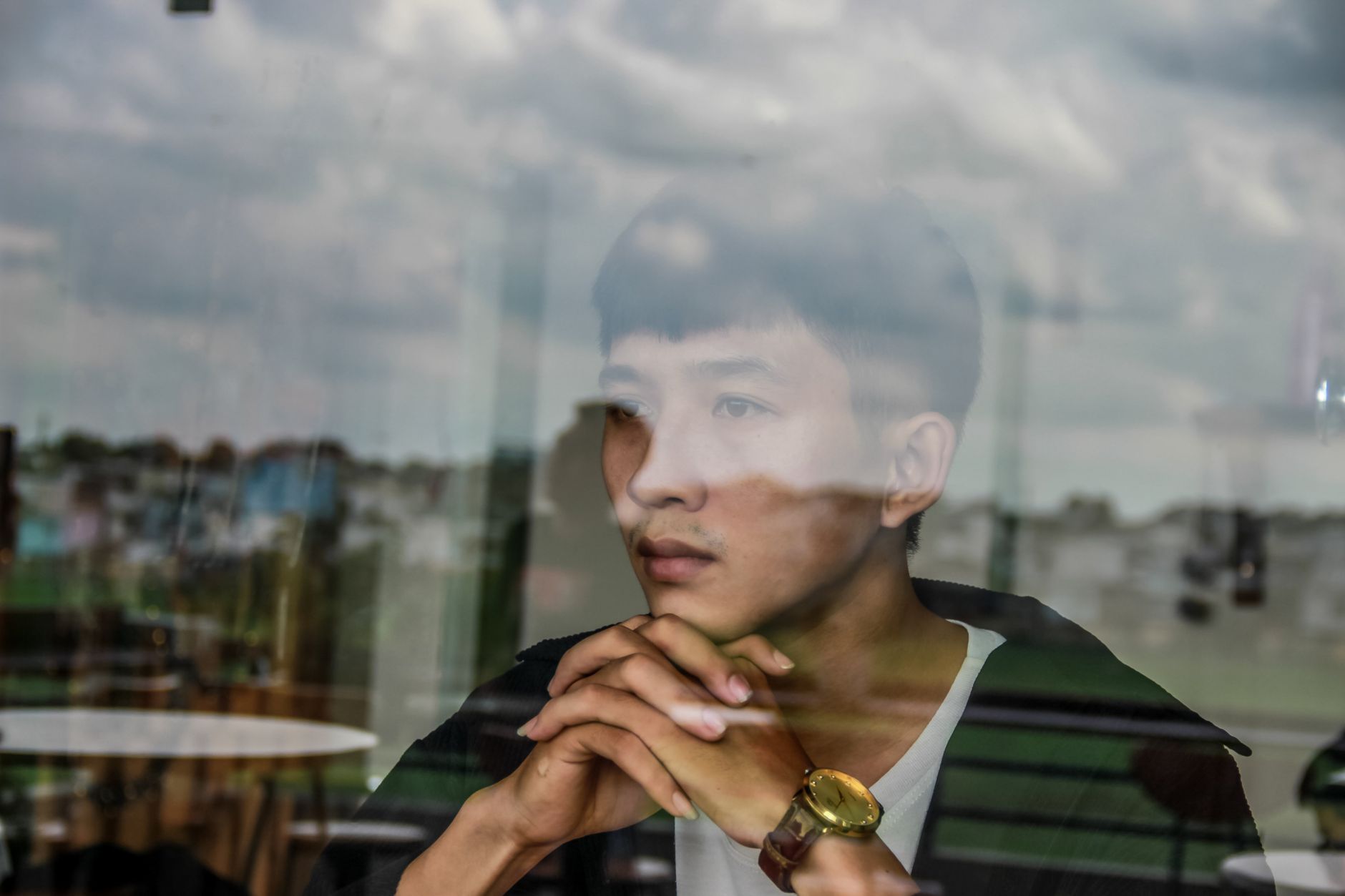 A person sitting alone by a window in quiet reflection, journal open on their lap