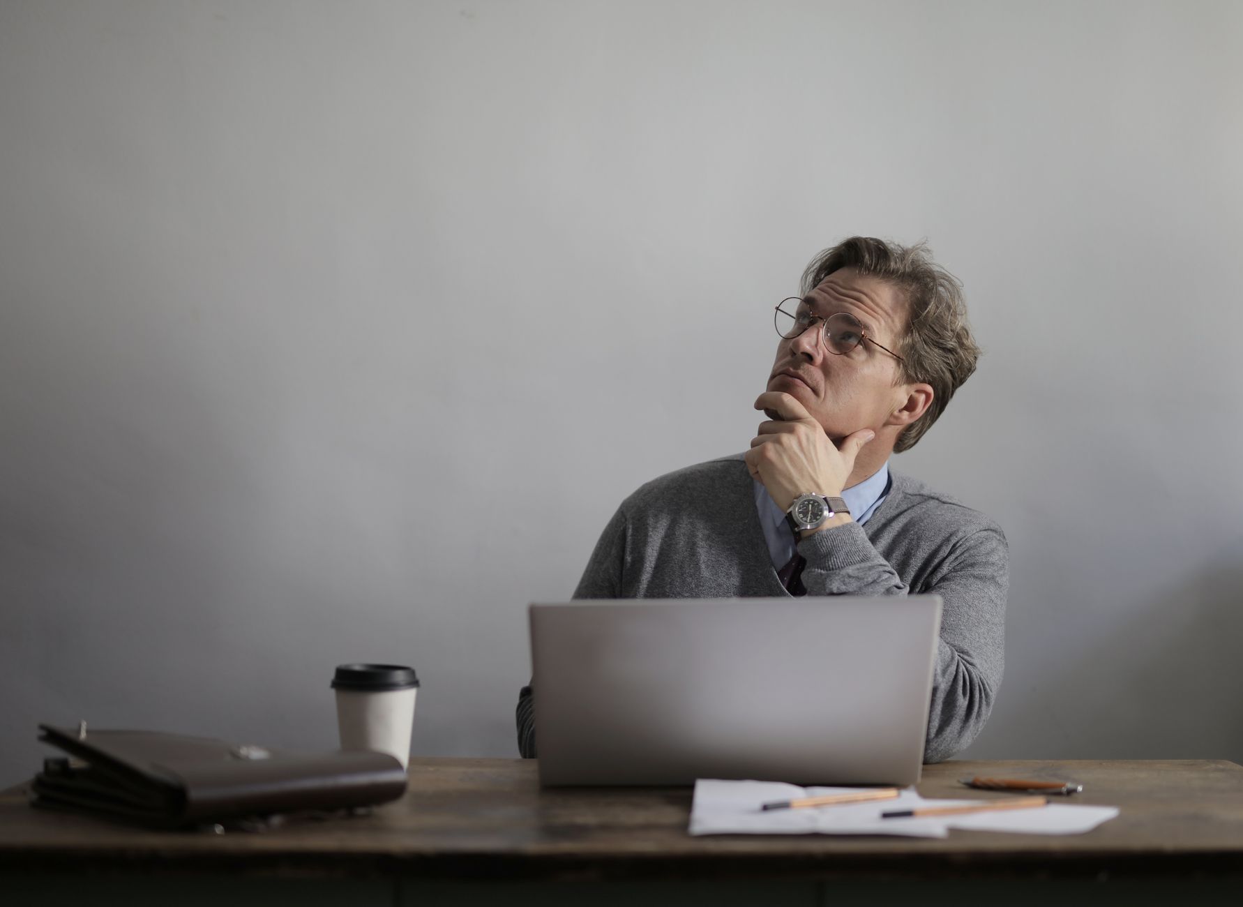 A job candidate sitting across a small table from an interviewer, mid-sentence with one hand raised, thinking through an answer