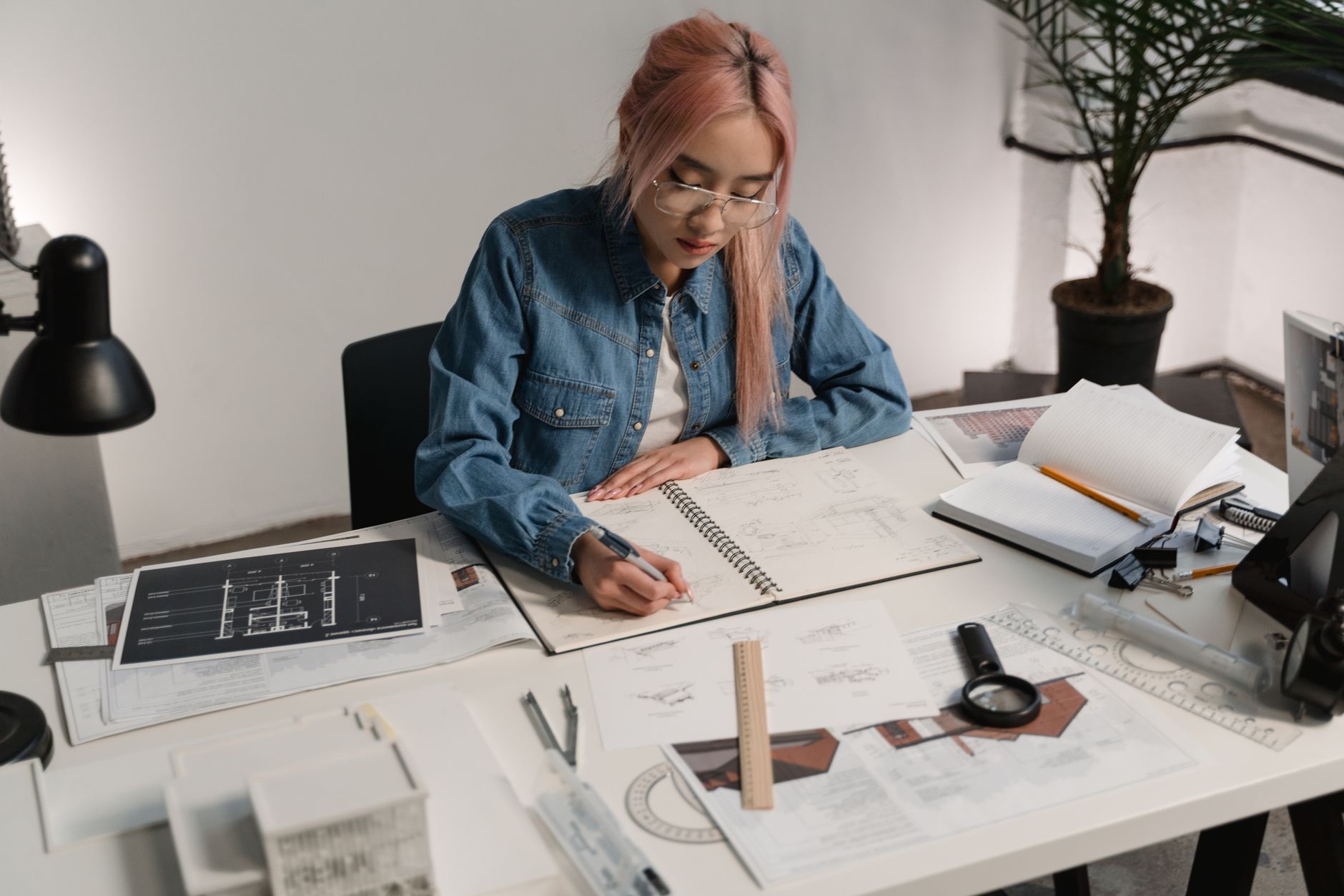 Woman architect working on project sketches at her desk in a contemporary office setting.