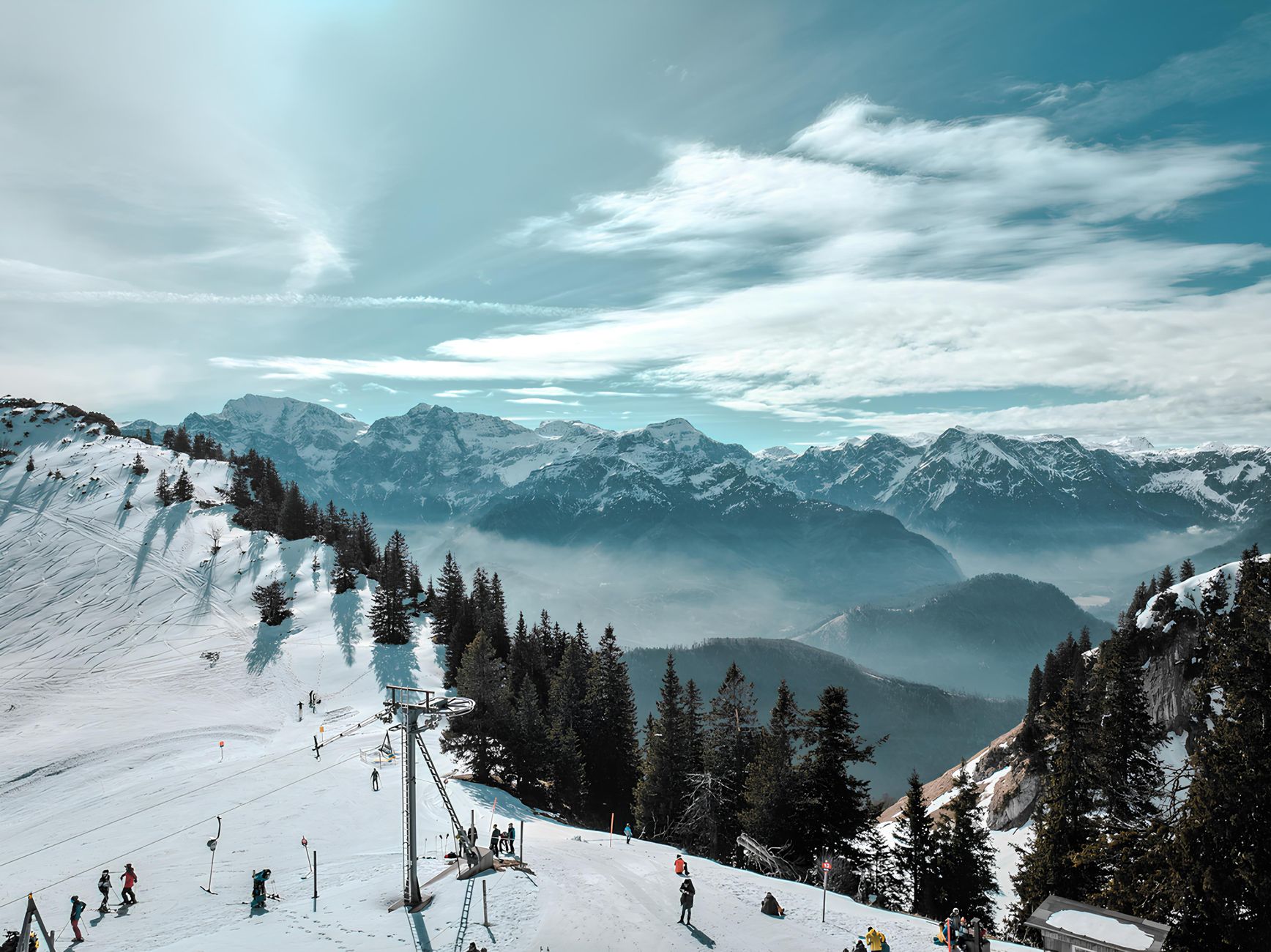 A small snowball at the top of a long, empty slope, the bottom of the hill disappearing into fog