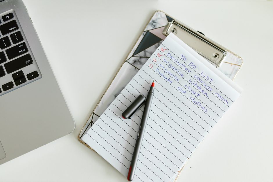 A checklist on a clipboard beside a laptop and pen.
