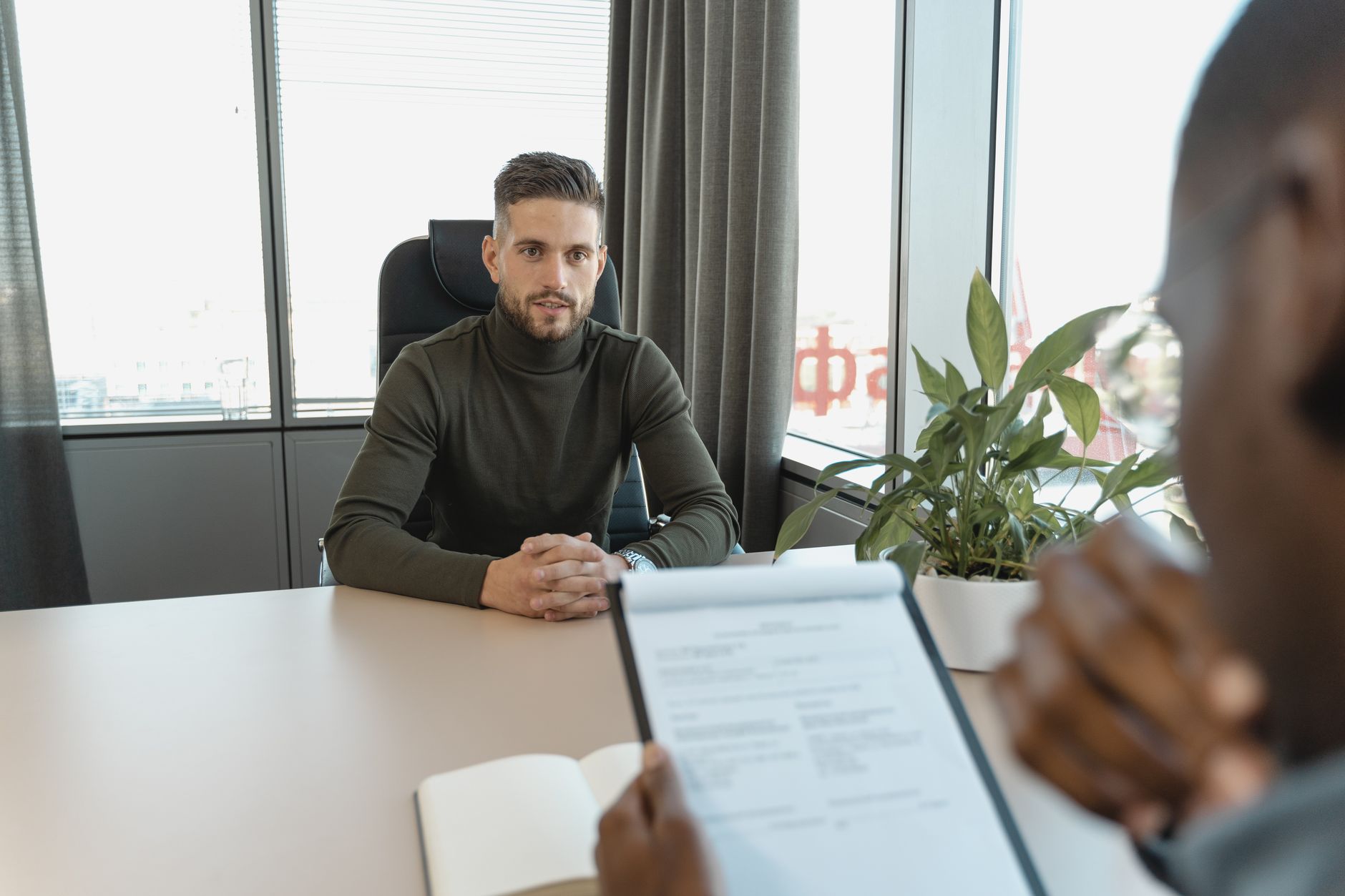 A candidate and interviewer seated across a small table mid-conversation, a resume between them