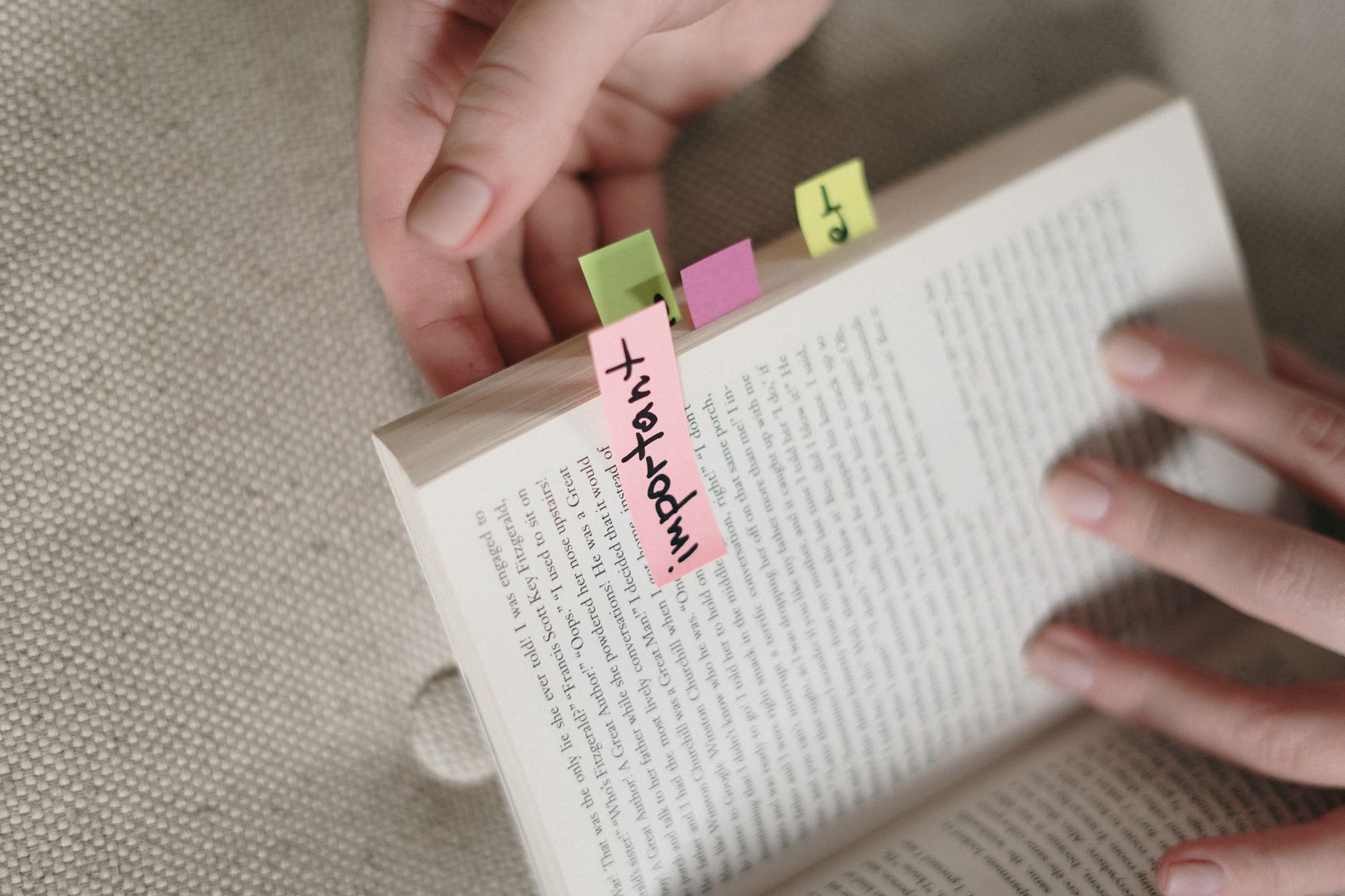 A reader highlighting a passage in a thick hardcover book