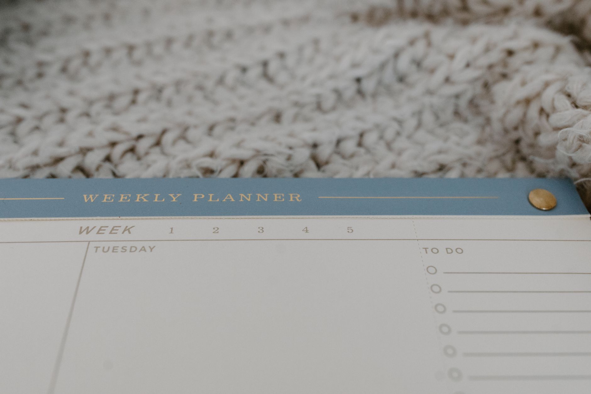Close-up of a minimalist weekly planner on a cozy textured surface, perfect for organizing tasks.