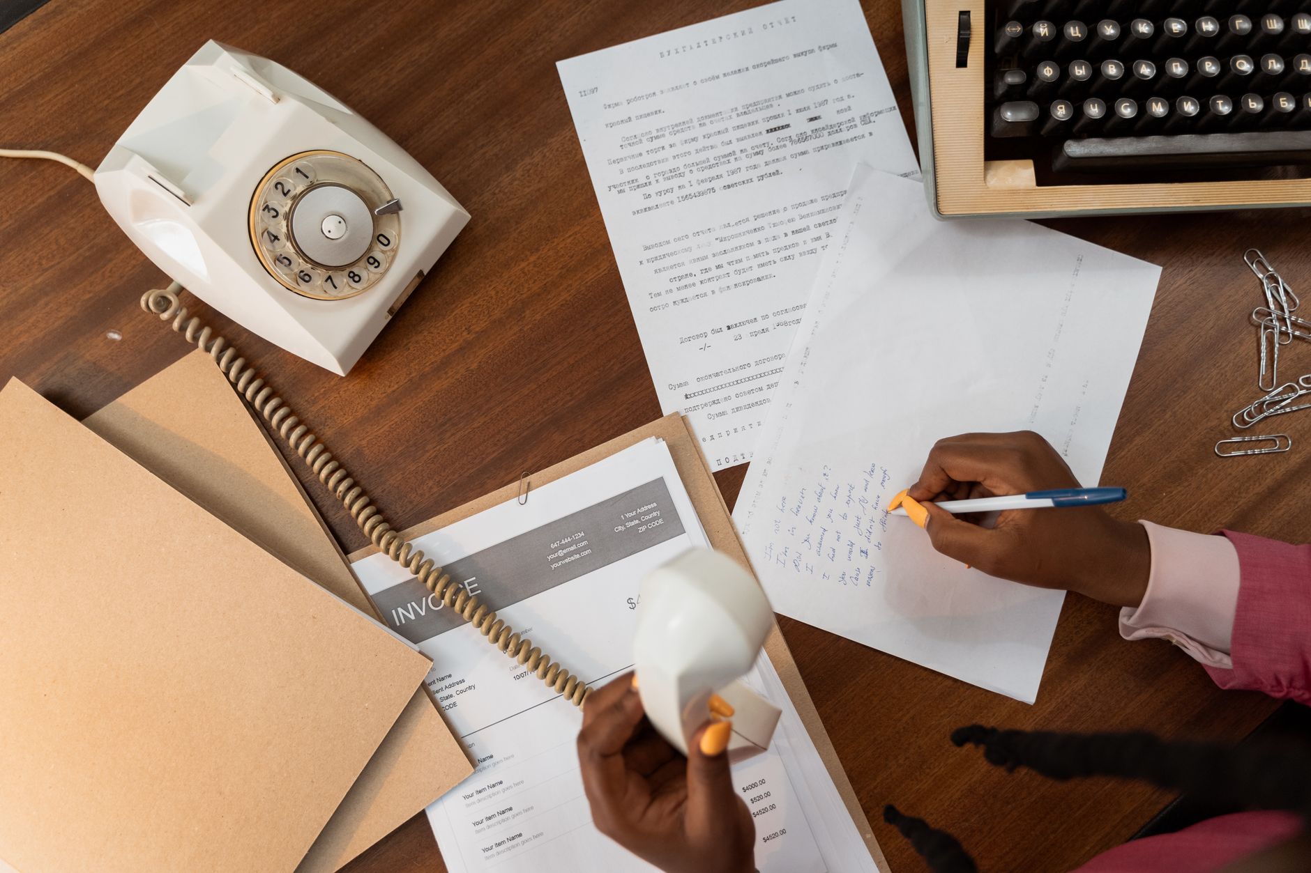 Person writing a professional note at a wooden desk