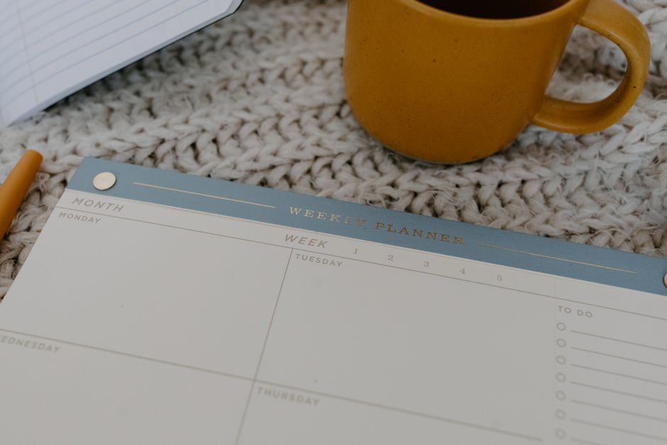 A weekly planner and coffee create a calm review ritual.