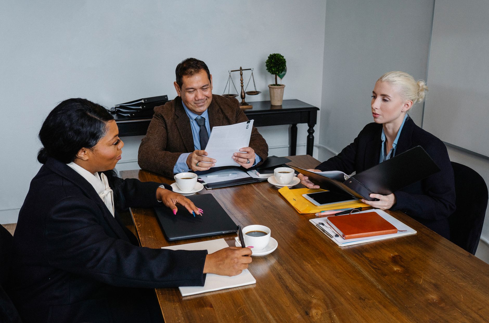 Two interviewers taking notes on clipboards while observing a candidate group discussion